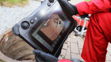 Inspector using a camera to look inside a storm drain